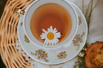 a cup of tea with a chamomile flower, on a picnic 