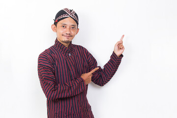 asian man with javanese traditional cloth lurik pointing with fingers to different directions isolated on white background