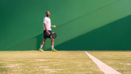 Padel player with black racket playing a match in the open behind the net court © REC Stock Footage