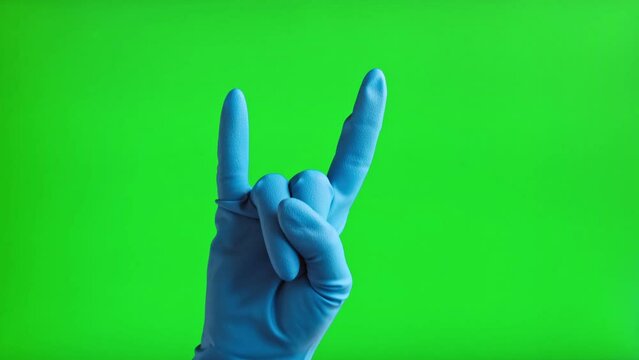 Hand in medical gloves gesturing rock icon Isolated On Green Screen Background. Close Up. Human Hand in blue glove making rock n roll gesture on Chroma Key Screen. 4K Footage. Horn sign.