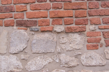 Half painted brick wall. Red brick wall and half-ruined white stucco, architecture close-up abstract background