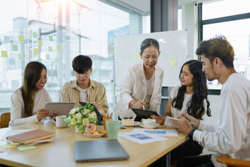 Group of Asian business people meeting, consulting and planning business on investment and market analysis for business development there are various analytical data document and using a laptop.