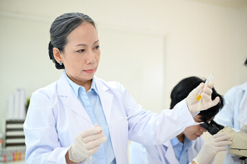 Professional Asian-aged female scientist working in the laboratory with her team