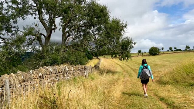 Young girl walking down a path on the route of the Cotswolds Way, a long distance footpath in England