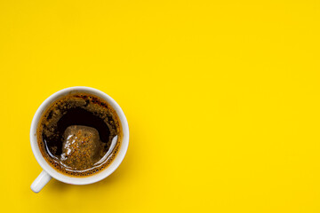 Frothy coffee in a porcelain cup on yellow background