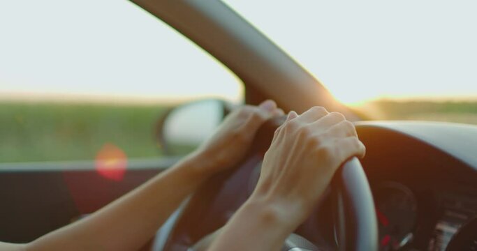 Close up female hands driving car outside city. Girl travels by car. Slow motion