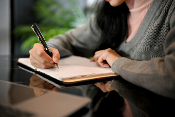 Female writing something on her diary. A female college student doing her homework