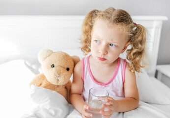 The child drinks water in bed. Drinking regimen during illness.
