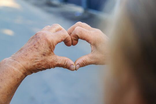 grandmother makes a heart with her hands. Selective focus.