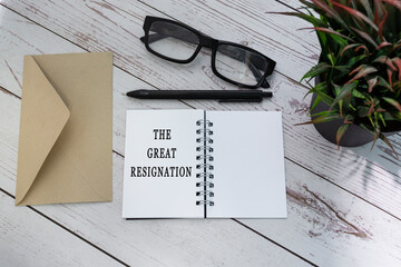 THE GREAT RESIGNATION text on notepad with brown envelop on wooden table.