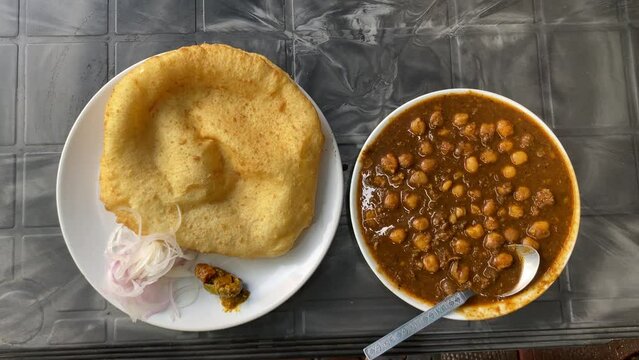 Breakfast food from India Chole Bhature, also known as poori, is a delectable Indian meal cooked with all purpose wheat flour and eaten with chickpea chana masala curry mixed pickles and sliced onion.