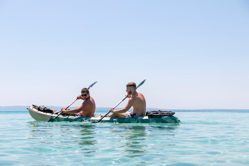 Happy two teenagers kayaking together in amazing clear water of Aegean sea.Happy family adventures concept