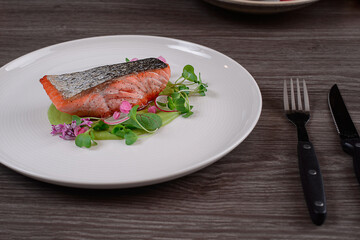 Fried salmon steak with potatoes and vegetables Grilled steak served with grilled tomatoes, salad, lemon sliced, pepper seeds, rosemary, parsley on white plate