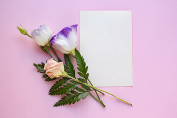 Minimalistic card mockup with  white eustoma flowers. Workspace. Wedding invitation cards, craft envelopes, lisianthus with copy space. Overhead view. Flat lay, top view 