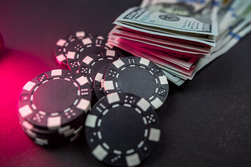 playing cards scattered with chips behind a roll of us dollars isolated on background.