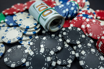 playing cards scattered with chips behind a roll of us dollars isolated on background.