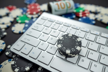 poker chips for poker with banknotes twisted placed on laptop keyboard.