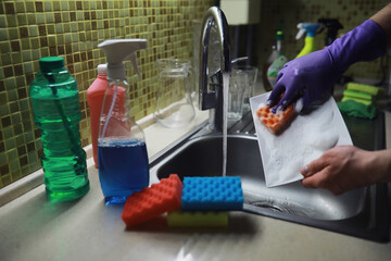 A bottle with an environmentally friendly dishwashing detergent on the background of a housewife washing dishes