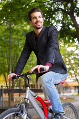 Young businessman riding bicycle in spring park