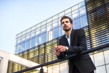 Young businessman standing in front of corporate office building