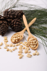 Heap of pine nuts and cedar cones on white background
