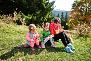 Naklejka na ściany i meble Mother with daughters enjoying in the mountains.The concept of family travel, adventure, and tourism. Lifestyle and hiking autumn vacations outdoor.