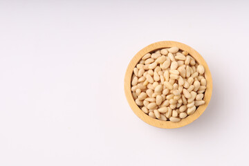 Heap of pine nuts and wood cup and cedar cones on on white background