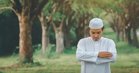 Religious muslim man  traditional kandura praying  outdoor at quiet nature  environment sun beams.