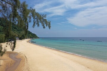 Tropical beach with stones and palm trees and a blue sea on Tioman Island in the South China Sea, belonging to Malaysia.