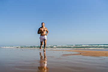 Chico joven tatuado y musculoso en ba&ntilde;ador y ropa interior en la playa