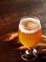 glass of craft beer on a wooden table , ears of wheat