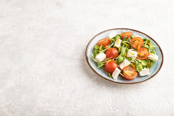 Vegetarian salad of tomatoes, marigold, microgreen, feta cheese on gray. Side view, copy space.