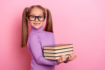 Photo of sweet lovely little girl with two tails help her teacher to hold book isolated on pink color background