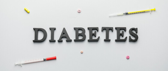 Word DIABETES, syringes and pills on light background