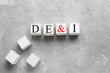 Wooden cubes with abbreviation DE and I (diversity, equity, inclusion) on grey background