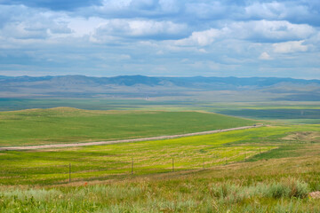 Bald Mountain in the Buryat Republic of Russia. Green hills against a blue sky with clouds.