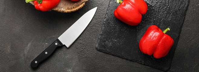Fresh red bell pepper with knife on dark background, top view