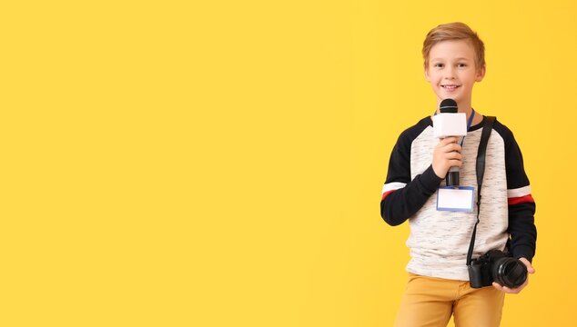 Little journalist with microphone and photo camera on yellow background with space for text