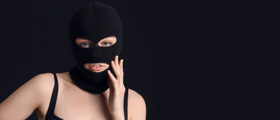 Young woman in balaclava on black background with space for text