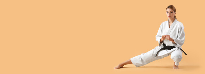 Fototapeta na wymiar Young woman practicing karate on beige background with space for text