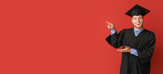 Young graduating student pointing at something on red background with space for text