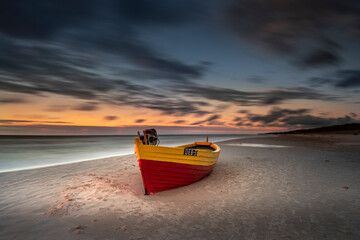 Kuter rybacki - statek, na plaży w Dębkach o zachodzie słońca nad morzem bałtyckim z widokiem na plażę