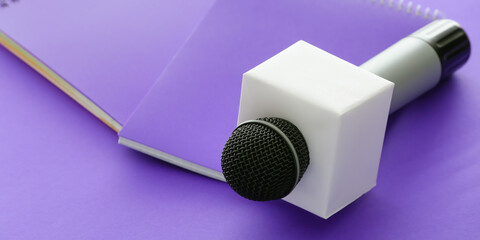 Journalist's microphone and notebooks on violet background