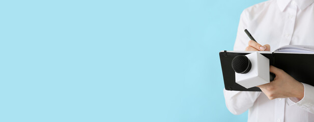 Journalist with microphone and notebook on light blue background with space for text