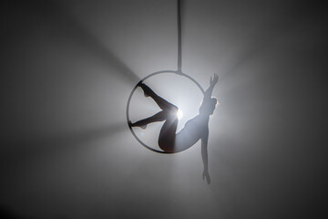Aerial acrobat in the air ring. Young woman performs the acrobatic elements in the air hoop....
