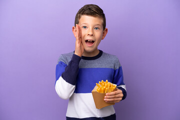 Little boy holding fried chips isolated on purple background with surprise and shocked facial expression