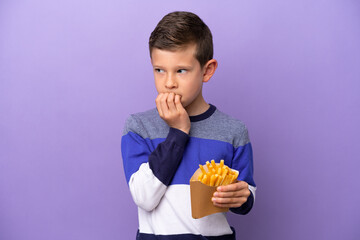 Little boy holding fried chips isolated on purple background having doubts