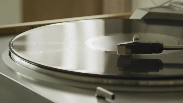 Modern vinyl turntable playing at home with window reflection on vinyl