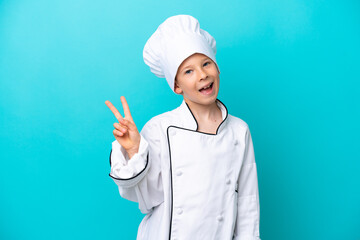 Little chef boy isolated on blue background smiling and showing victory sign