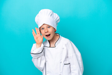 Little chef boy isolated on blue background listening to something by putting hand on the ear